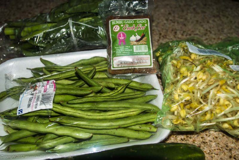 Green beans, cucumber, bean sprouts and leafy green vegetables to be used in gado gado recipe. Also visible: package of gado gado peanut sauce