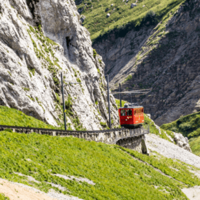 Red train goes down the track on Mount Pilatus. Text block says Mount Pilatus cogwheel train