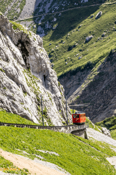 Red train goes down the track on Mount Pilatus.