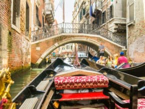 Front of Venetian gondola, as seen by passenger. Bridge and oncoming gondola in background