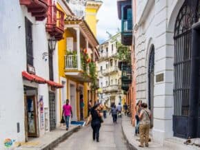 Buildings line a narrow street in Cartagena. People in the street.