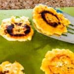 Spatula holding freshly prepared fried green plantain chip, aka patacones or tostones