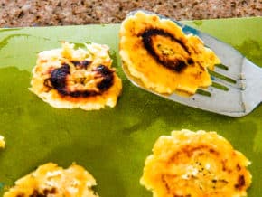 Spatula holding freshly prepared fried green plantain chip, aka patacones or tostones