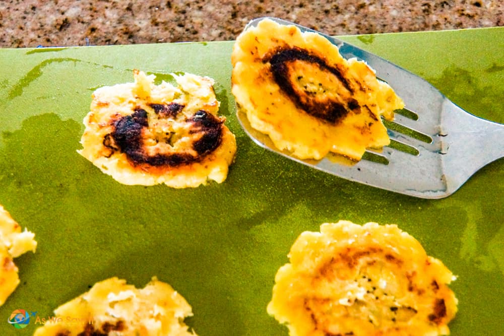 Spatula holding freshly prepared fried green plantain chip, aka patacones or tostones