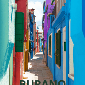 Colorful houses line a sidewalk in Burano Italy. Text overlay says Burano What to See & Do
