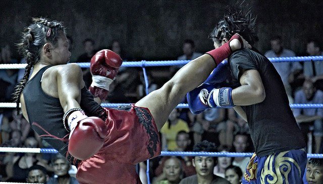 Muai Thai boxer landing roundhouse kick to side of opponent