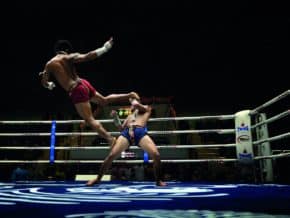 muay thai fighter deals an airborne kick in a Bangkok stadium