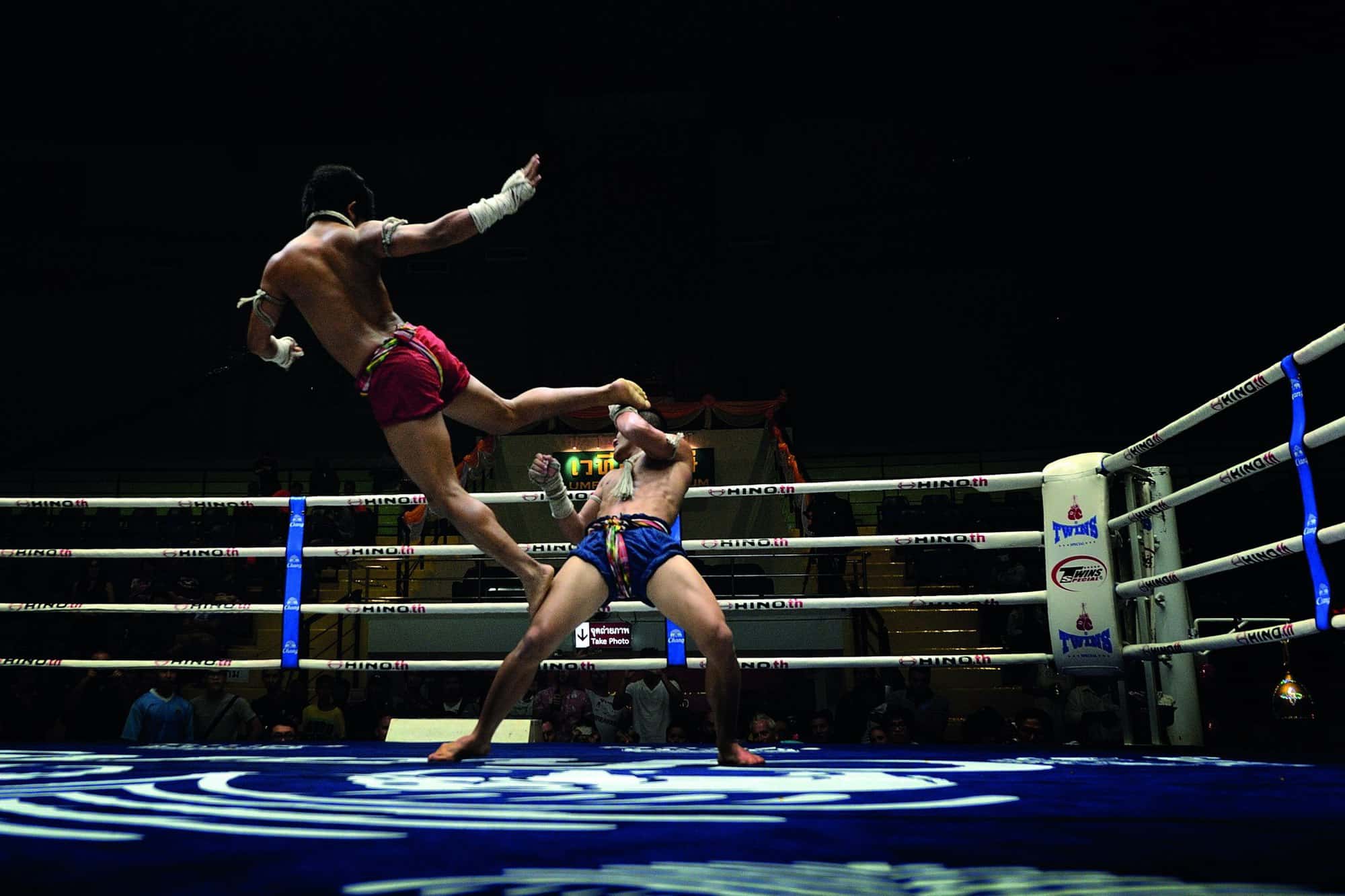 muay thai fighter deals an airborne kick in a Bangkok stadium