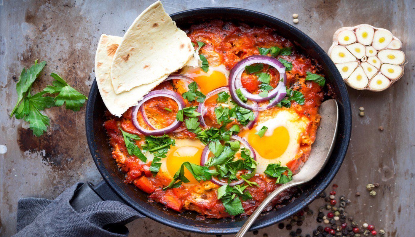 Skillet with Shakshuka, topped with a couple of pieces of flatbread.