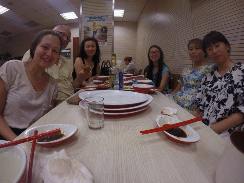 author sits with Chinese people at long table after dinner