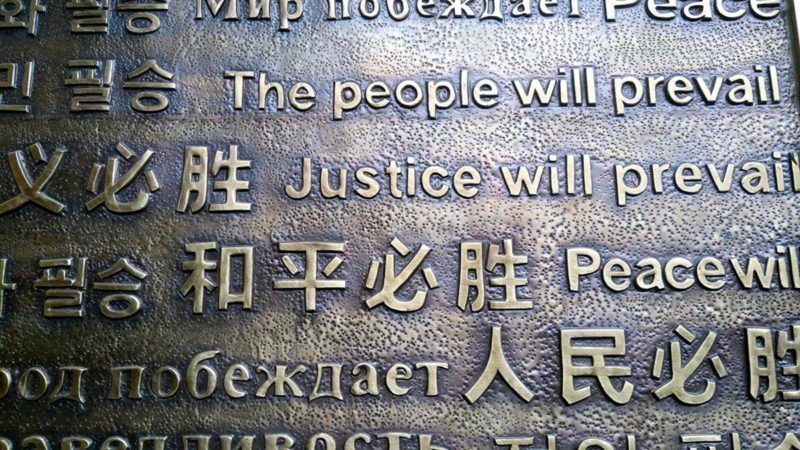 Multilingual metal sign says The People will prevail, justicde will prevail and Peace will prevail