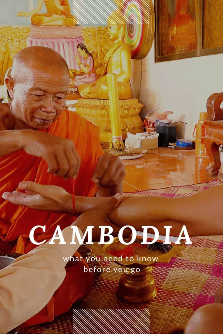 khmer monk tying red thread around someone's wrist