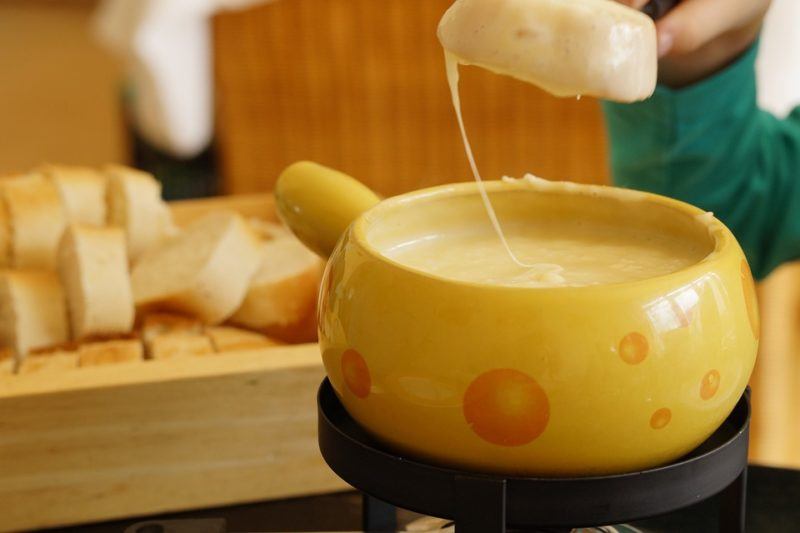 Bread dripping a string of cheese above a pot of Swiss fondue.