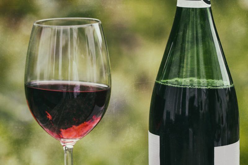 Closeup of a glass of red wine and a bottle of red wine 