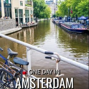 Amsterdam canal with cruise tour boats park along edge. Bicycle on bridge in foreground
