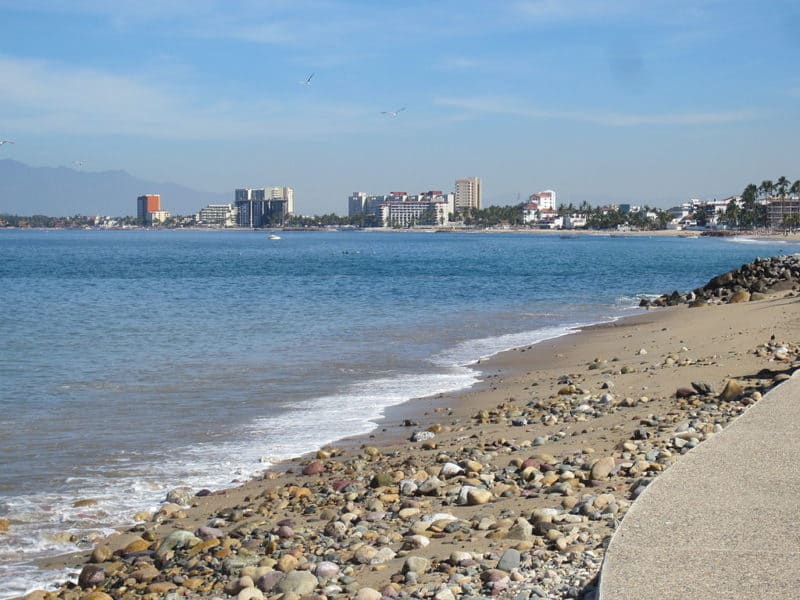 Calm ocean waves with puerto vallarta cityscape in background, as seen fron the esplanade.