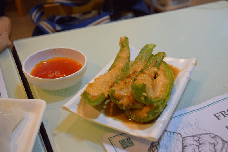 stuffed pepper halves on a platter with sweet and sour dipping sauce in a nearby bowl