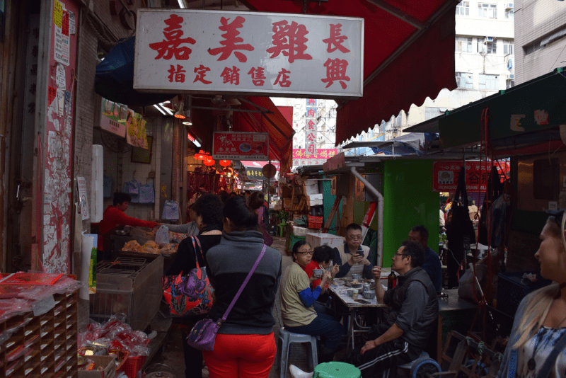 Crowded alleyway in Hong Kong full of street food vendors and tables