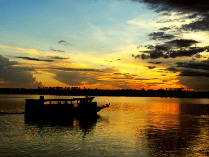 brilliant sunset silhouettes a boat on the Amazon River