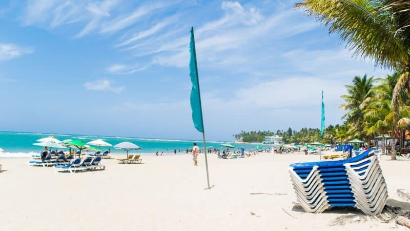 Turquoise water as seen from Costa del Sol beach. Stack of blue lounge chairs in foreground