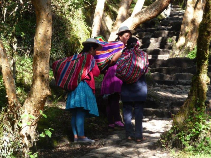 3 Peruvian women in hats carry large colorful bags.over their shoulders. They probably wouldn't find the Inca Trail walk hard at all.