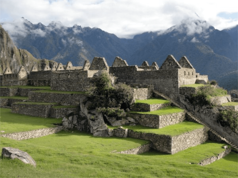 Machu Picchu ruins and walled rock terraces and low-hanging clouds overhead