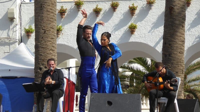 Couple dancing flamenco on a stage in Southern Spain with two guitarists in background. 