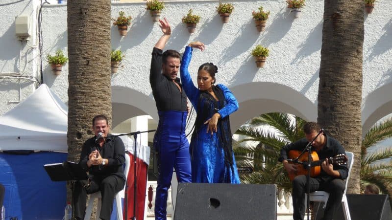 Couple dancing flamenco on a stage in Southern Spain with two guitarists in background.