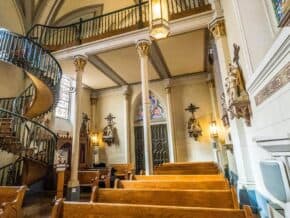 Spiral staircase and pews in the back of Loretto Chapel