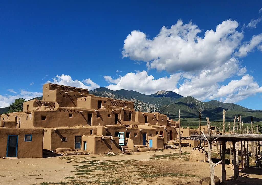 Taos Pueblo framed by mountains and blue sky.