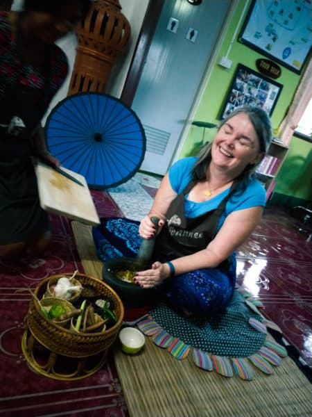 Linda pounds chilies in a mortar and pestle. Thai curry ingredients in the foreground