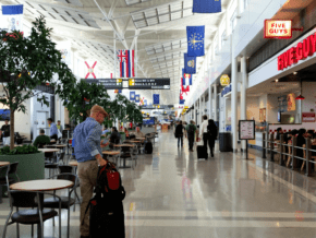 Man wheeling luggage through airport departures area