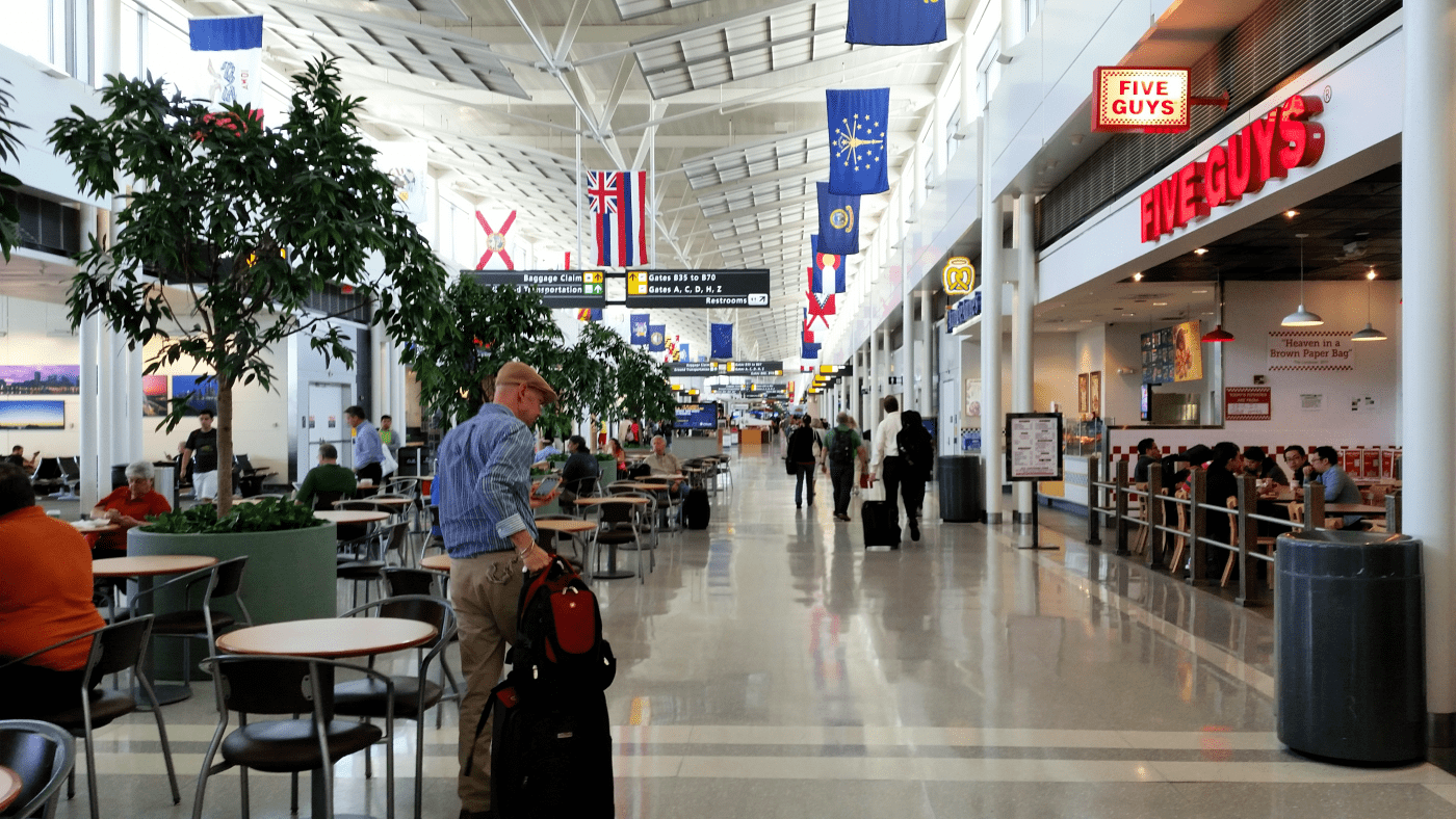 Man wheeling luggage through airport departures area