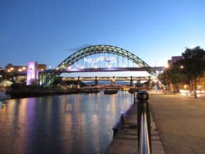 Newcastle quayside at twilight. View down the walkway and River Tyne toward bridge in background.