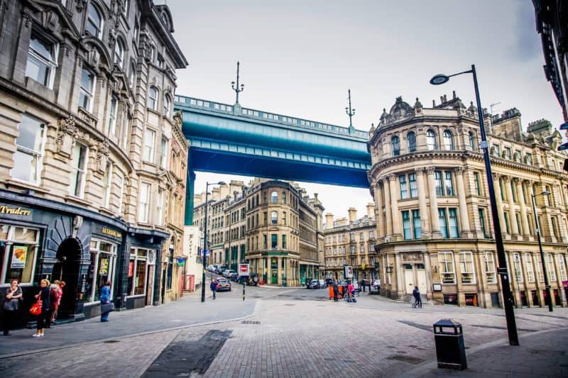Street in Newcastle with a metal bridge above old buildings