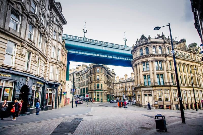 Street in Newcastle with a metal bridge above old buildings 