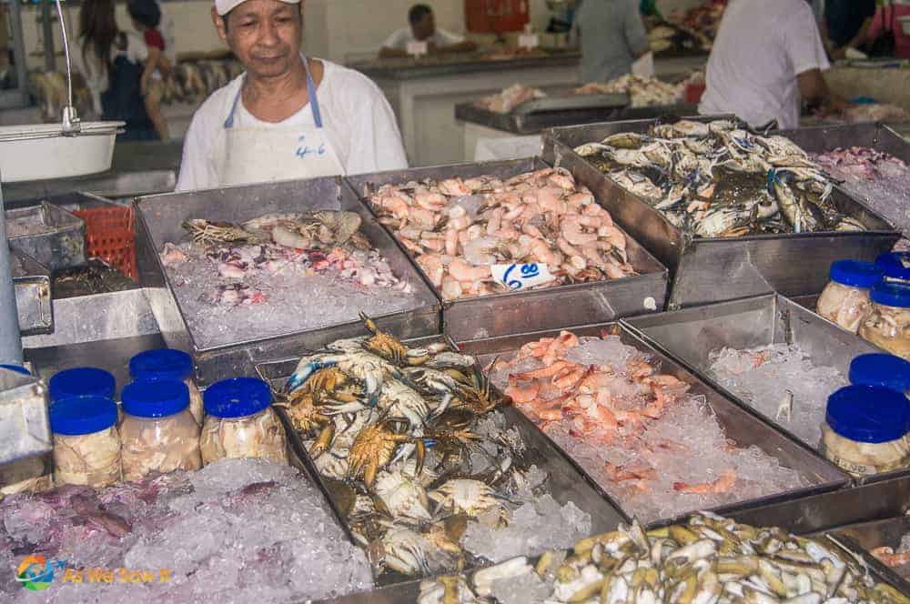 Man stands behind bins of seafood on ice at the fish market in Panama City Panama