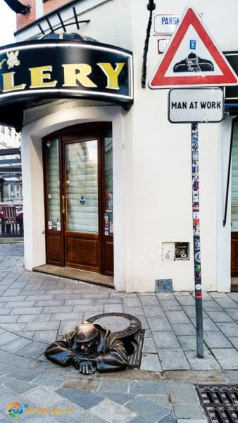 a bronze statue of a worker emerging from a manhole cover. His name is Cumil, and he isone of the quirky statues in Bratislava.