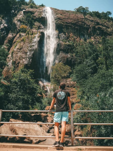 Woman leaning on a railing in foreground looking at Diyaluma Falls in background