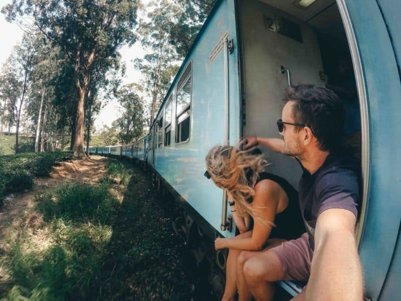 People sitting on the doorway of the Ella to Kandy train