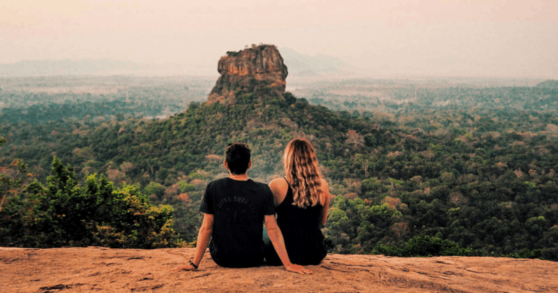 Couple sitting on a cliff looking out to Sigiriya Rock