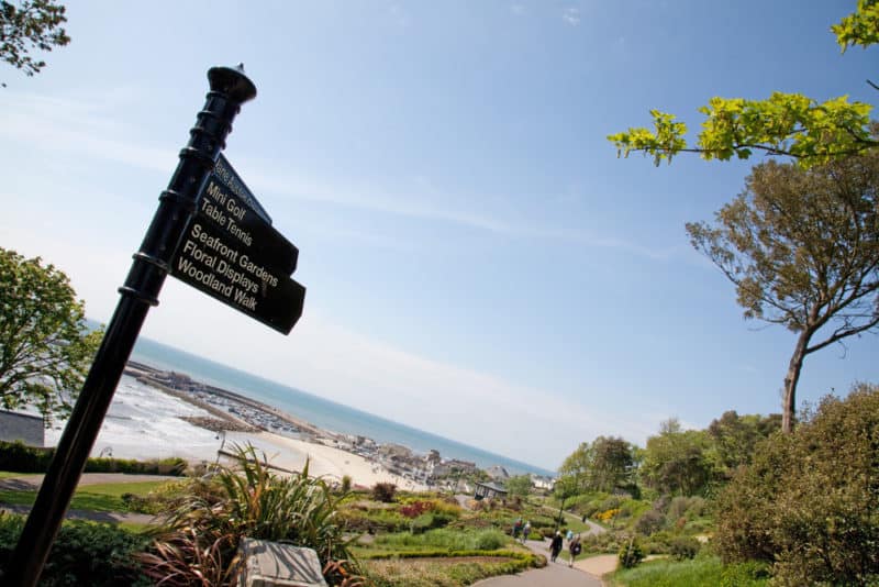 pathway along beach with a sign saying mini golf table tennis seafront gardens floral display woodland walk