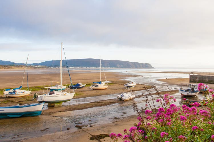 boats resting on the muddy floor of abersoch waiting for the return of the tide waters