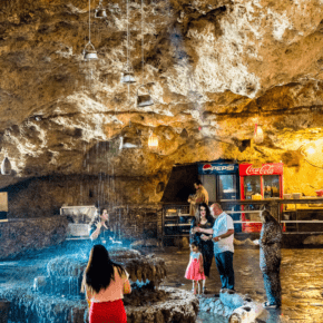 People standing around a waterfall at Inishke cave. Text overlay says What to see and do in Iraq