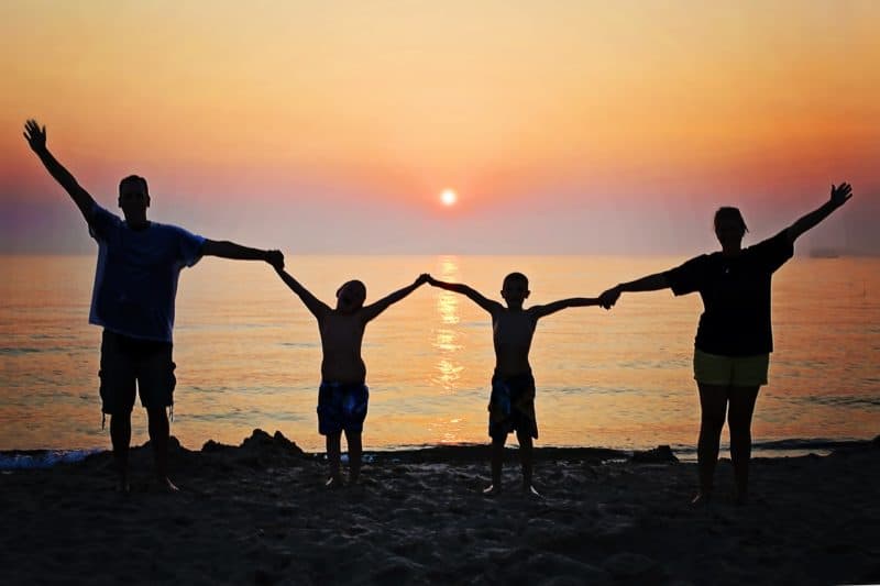 family holding hands on the beach at sunet