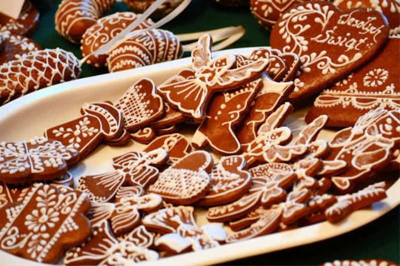 plate full of German lebkuchen in various shapes and sizes. Mostly angels and hearts, all decorated with icing.