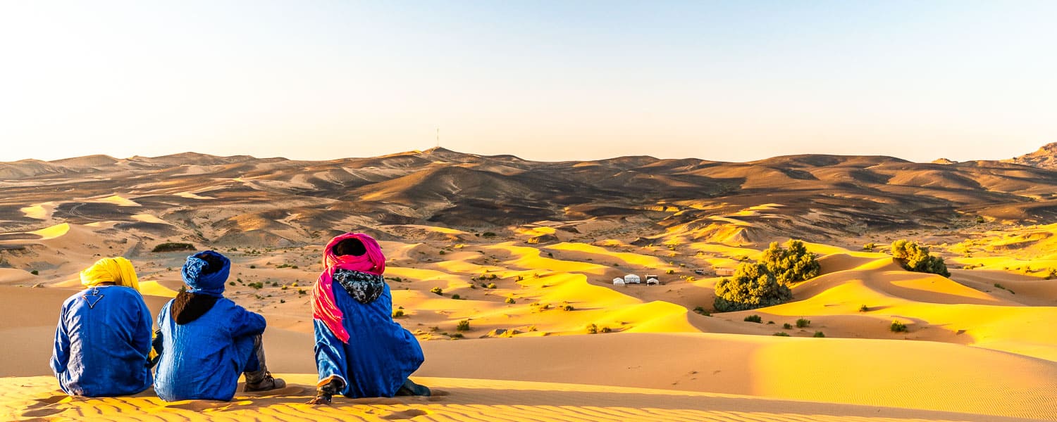 Bedouins enjoying the sunset across the Sahara sand dunes.