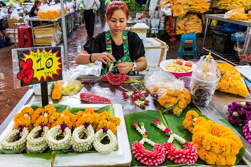 Woman creating a flower garland in Bangkok flower market