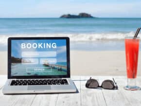 laptop with sunglasses and a drink on the beach. text says booking