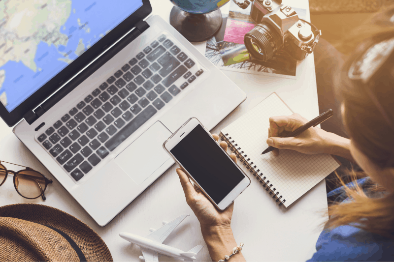 man booking an international flight on laptop with cellphone in hand